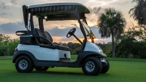 Golf cart on the green with the sun setting